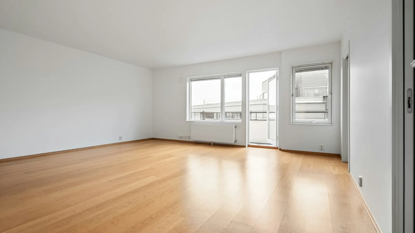 Leere, helle Wohnung mit Holzboden und weißen Wänden