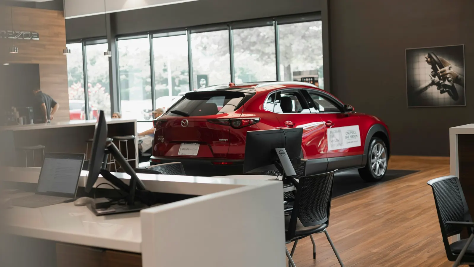 Ausstellungsraum eines Autohauses mit rotem Fahrzeug und Beratungstisch