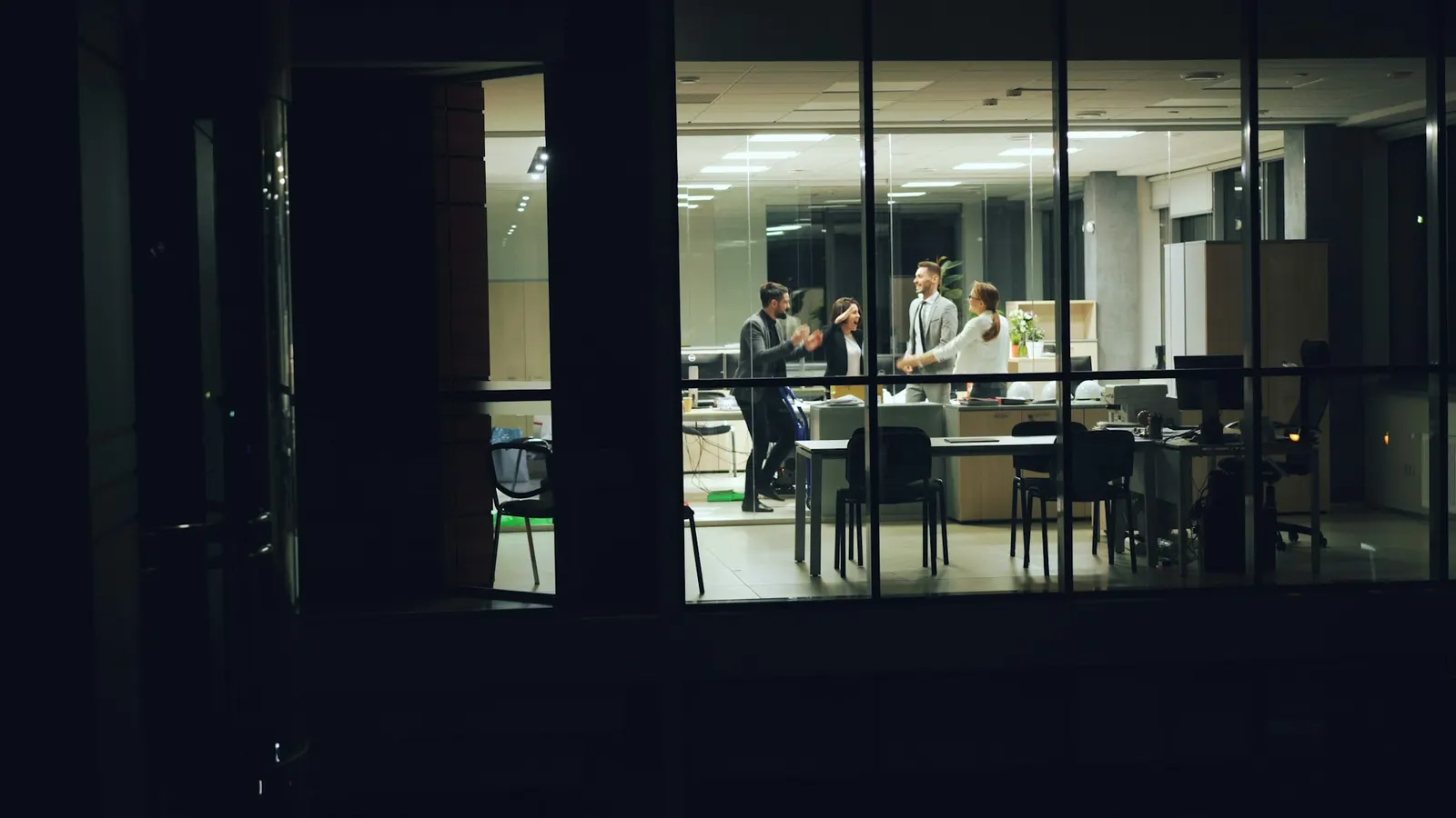 Beleuchtetes Büro am Abend, von außen durch die Fenster gesehen